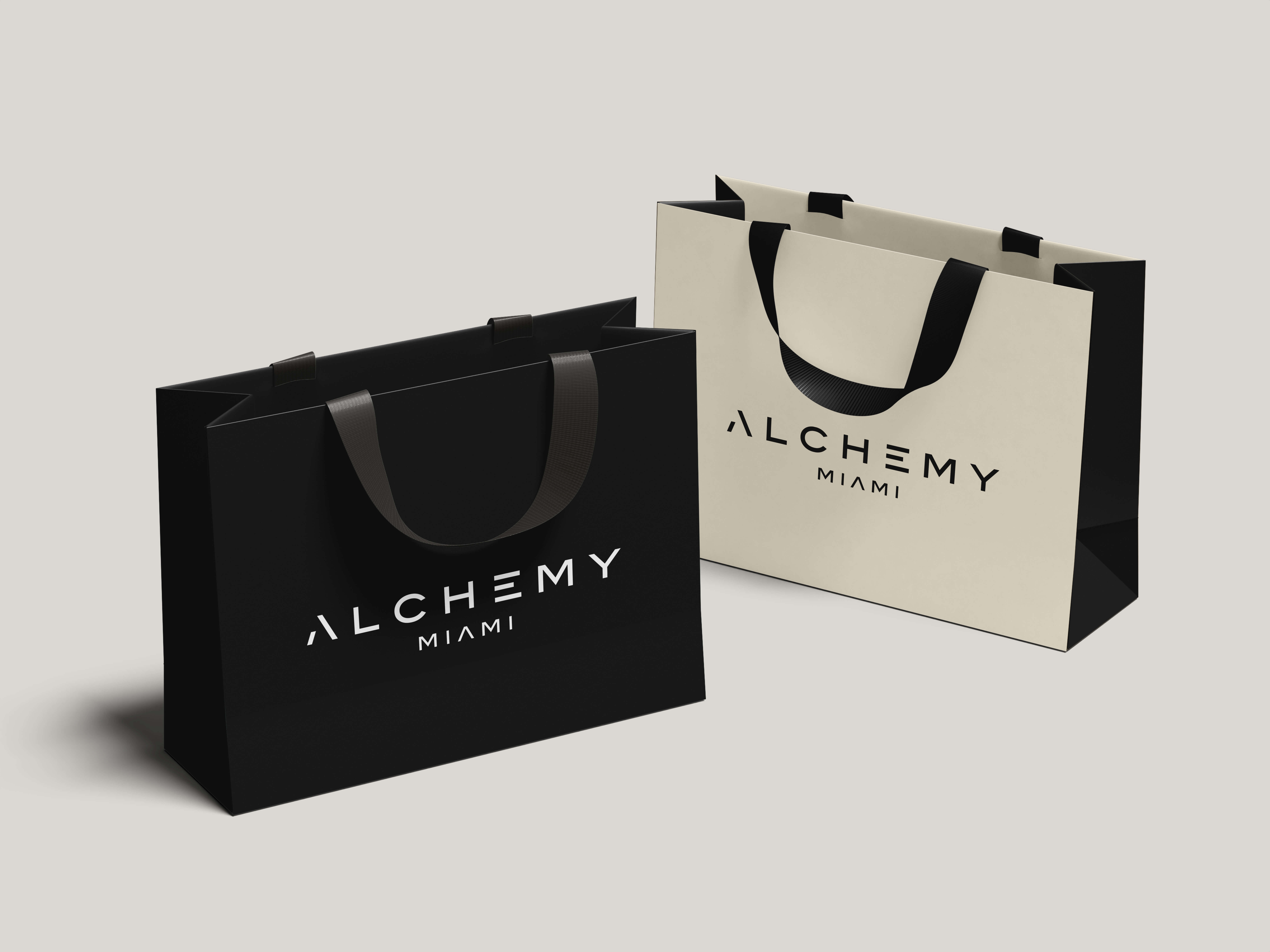 Two Alchemy branded bags. One white and one black with Alchemy logo in the center of the bag