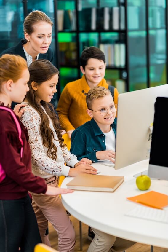 Elementary school students and teacher around a computer