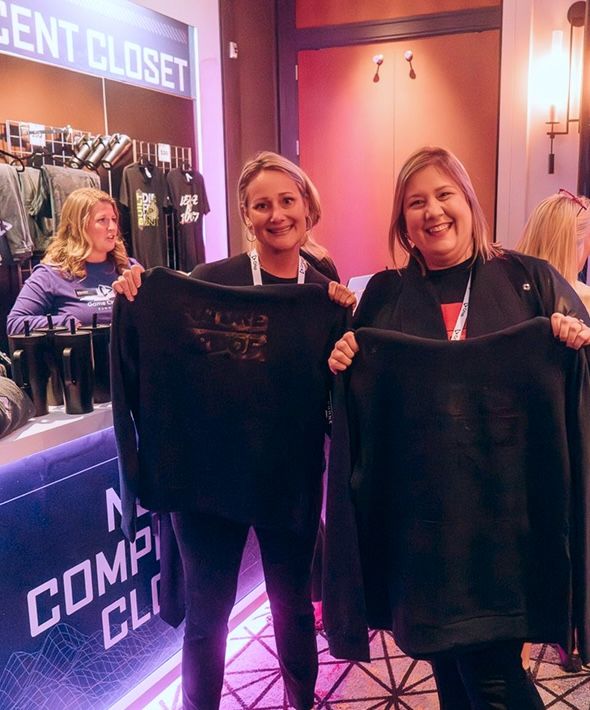 Two women holding up their new shirts